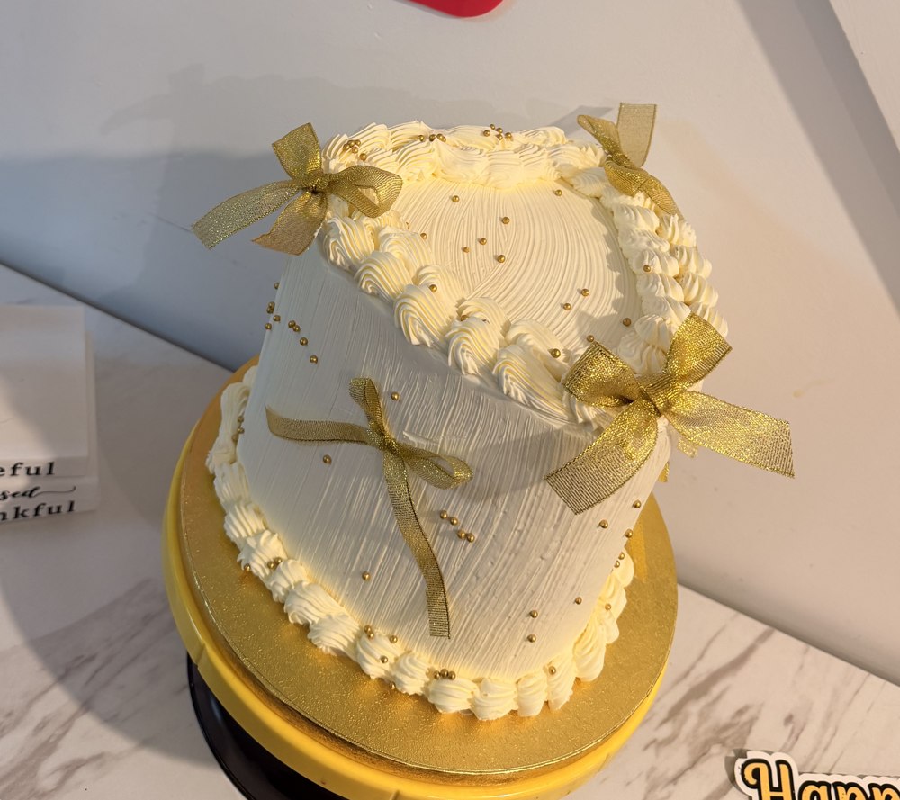 Elegant white and gold two-tier Anjiecakes celebration cake with hand-tied ribbon bows